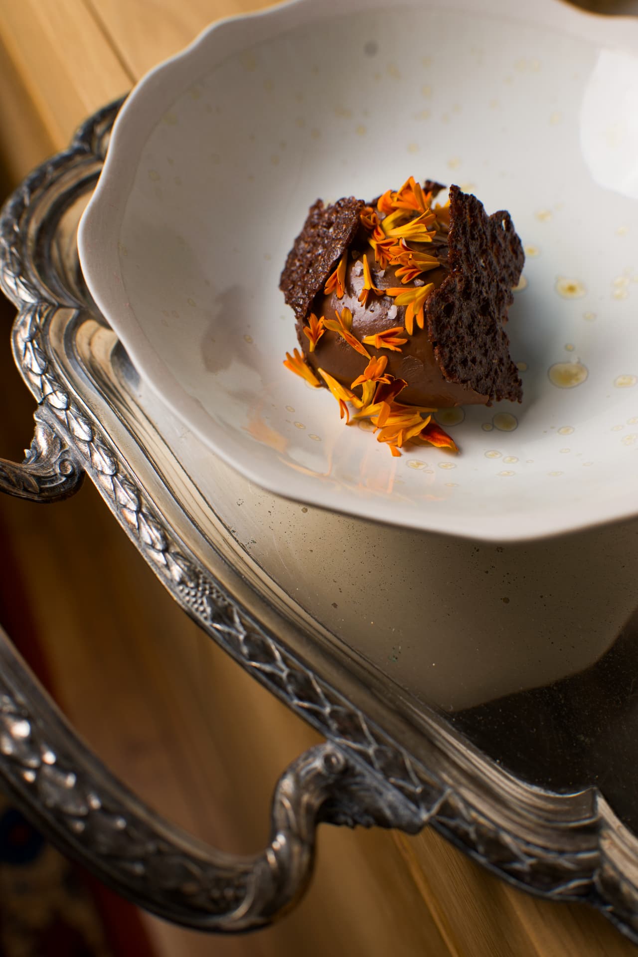 Dessert au chocolat, fleurs comestibles et tuile, sur un plateau argenté