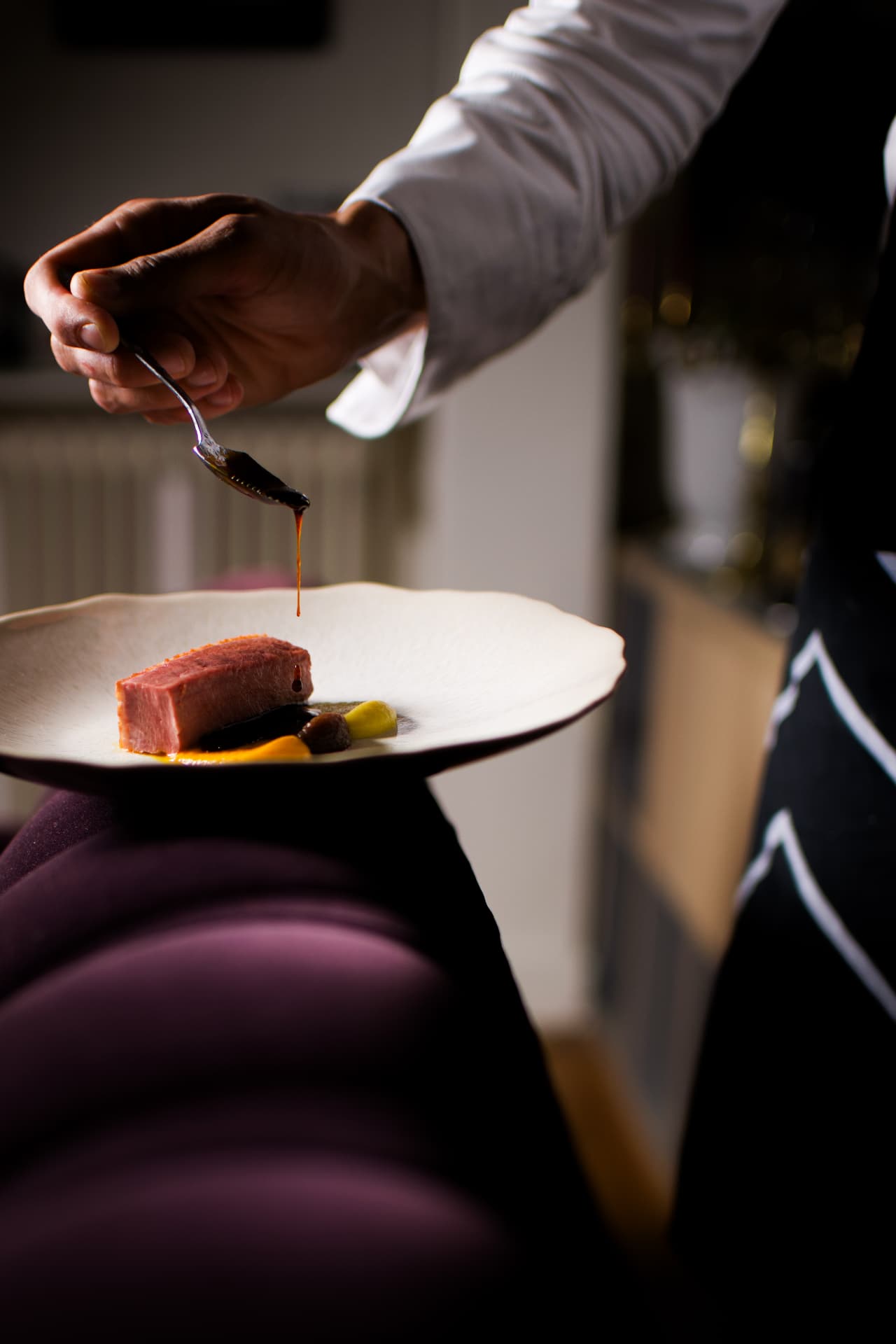 Le chef assaisonne son plat dans le salon, lumière tamisée